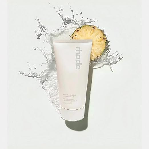 Tube of 'rhode' product with a pineapple slice on a light background