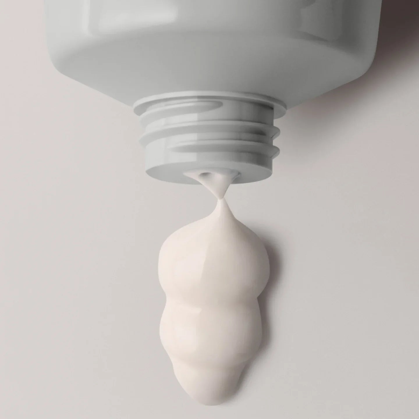 Close-up of a white tube with cream being squeezed out on a light gray background