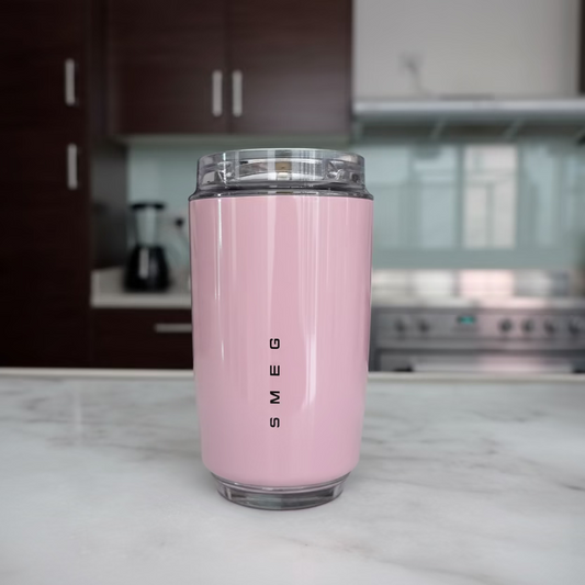 Pink tumbler with 'SMEG' branding on a kitchen counter