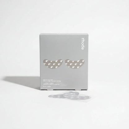 Two eye patches on a wooden surface with a box labeled 'rhode' in the background.