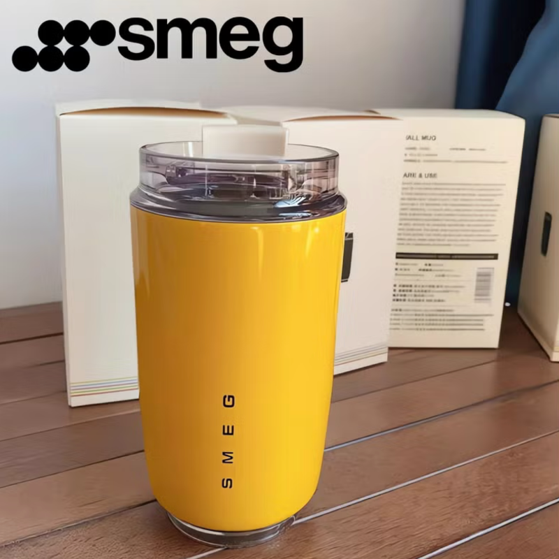 Yellow Smeg coffee grinder on a wooden surface with packaging in the background.