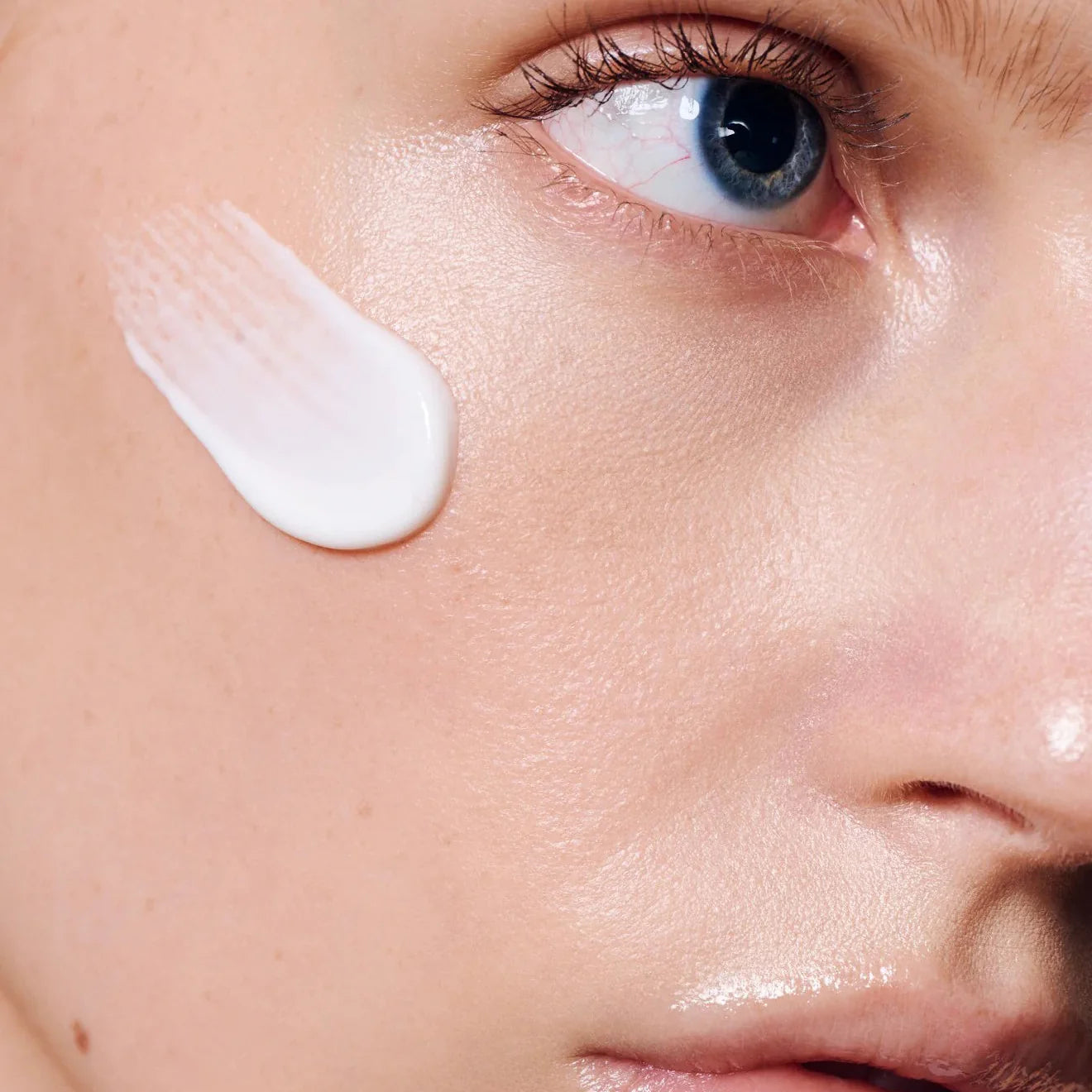 Close-up of a person's face with a skincare product applied to the cheek.