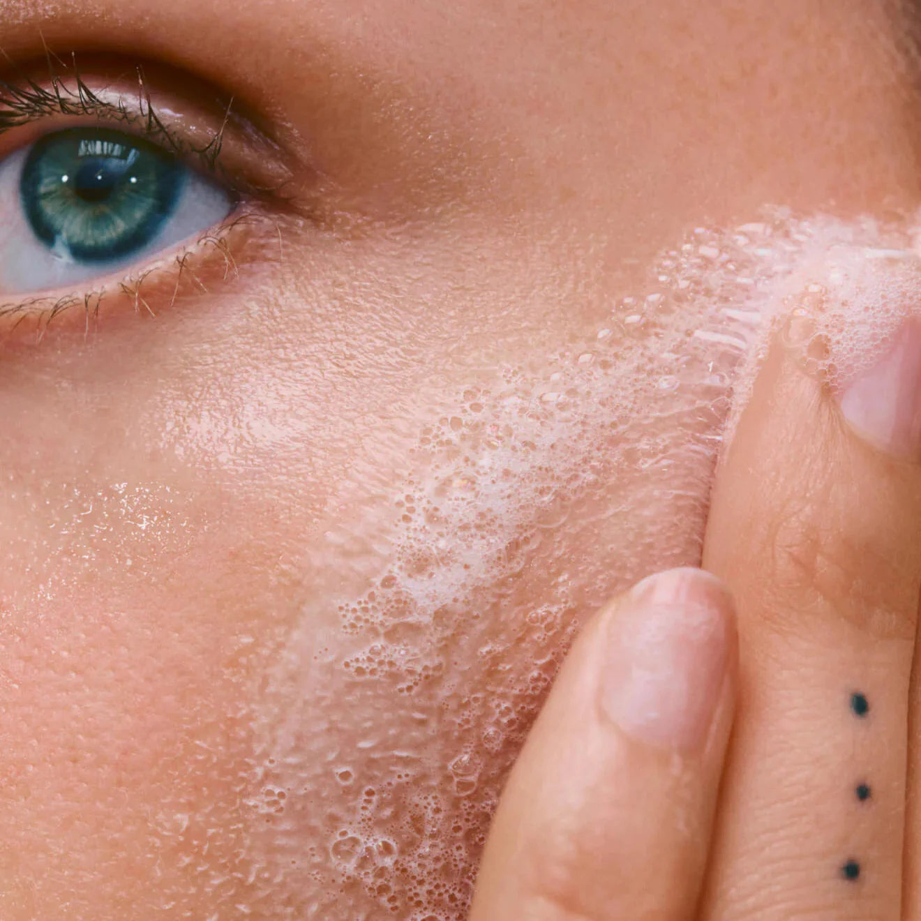 Close-up of a person applying a skincare product to their face.